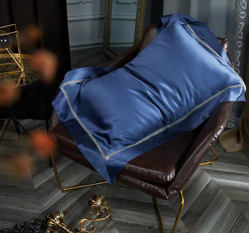 A dark brown leather armchair with a blue satin pillow resting on it, placed on a wooden floor.