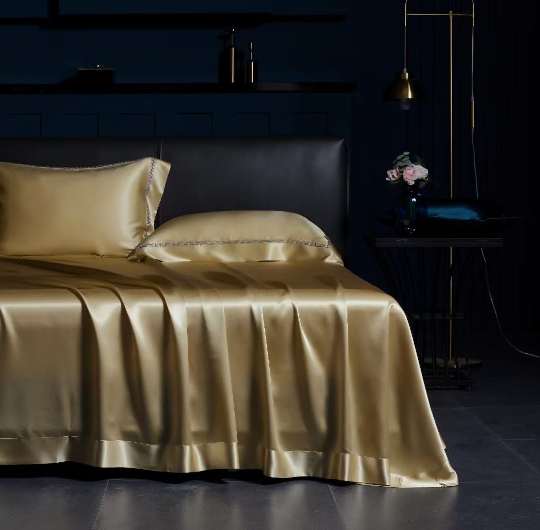 a luxurious bedroom setting with a bed dressed in a gold satin bedspread and matching pillowcases. The bed is positioned against a dark blue wall, creating a striking contrast. On the nightstand next to the bed, there is a vase with flowers, adding a touch of elegance to the scene. The overall atmosphere of the image is sophisticated and inviting.