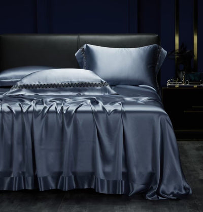 A luxurious bed with a satin bedspread and matching pillows, set against a dark blue background.