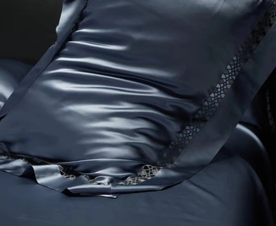 A close-up view of a dark blue satin pillowcase with a decorative trim.