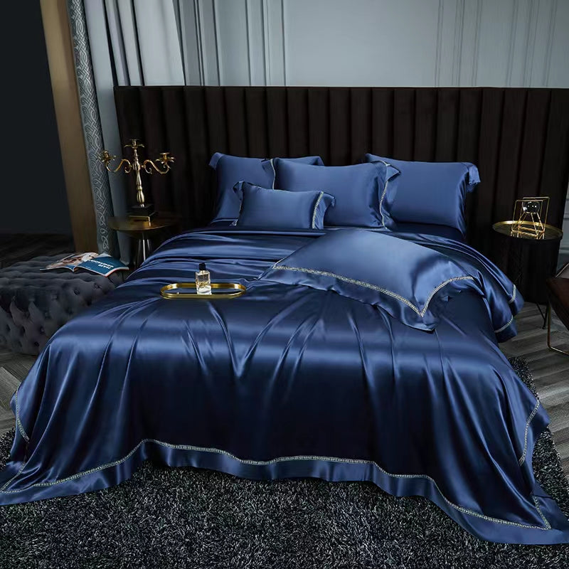 a luxurious bedroom with a large bed dressed in a blue satin bedspread and matching pillows. The bed is framed by a dark headboard, creating a sense of elegance and sophistication. The room also features a side table with a lamp and a tray, adding to the overall ambiance of the space.