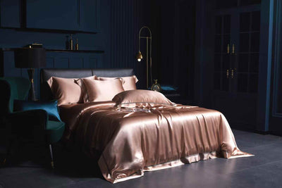 A luxurious bedroom with a large bed covered in a satin bedspread, a black headboard, and a gold lamp. The room has dark blue walls and a dark floor, creating a sophisticated and elegant atmosphere.